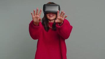 Young woman using virtual reality headset helmet to play simulation game app, watching content video