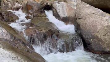 waterfall cascades down rugged rocks surrounded by lush greenery. The flowing water glistens in the sunlight, creating a tranquil and refreshing ambiance, Stunning depictions of nature are raw beauty video