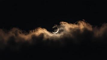 Crescent moon peeking through clouds in the night sky during a serene atmosphere photo