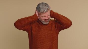 Annoyed irritated senior man covering ears, gesturing No avoiding advice ignoring noise loud voices video