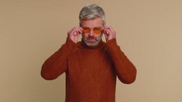 Happy middle-aged old man wearing sunglasses, charming smile, celebrating success, winning, flirting video