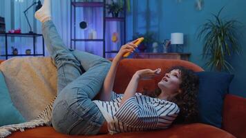 Portrait of young woman lying on sofa, using smartphone share messages on social media application video
