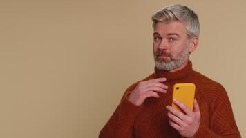 Middle-aged old man using smartphone pointing empty place, advertising area for mobile application video
