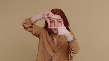 Woman photographer gesturing picture frame with hands, looks through fingers and focusing on object video