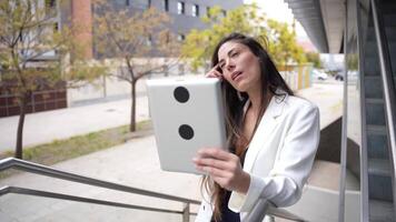A woman is utilizing a tablet while enjoying the outdoors in an urban city setting video