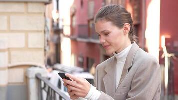 A young woman is engrossed in texting on her smartphone while sitting in an urban setting video