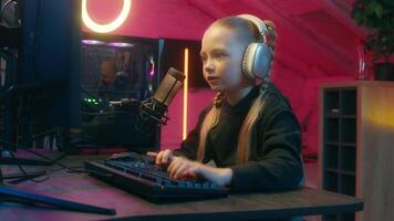Caucasian talking to microphone little girl gamer worried difficult hard competition streaming typing keyboard lost loose failure daughter kid child playing computer virtual game at home upset video