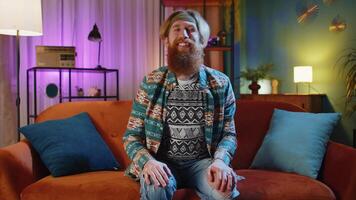 Hippie man at night home smiling at camera and waving hands gesturing hello, hi, greeting or goodbye video