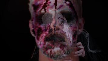 Close-up of sinister man with horrible scary Halloween zombie make-up blood flows and drips on face video