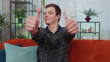 Happy young man looking approvingly at camera showing thumbs up, like positive sign, good news video