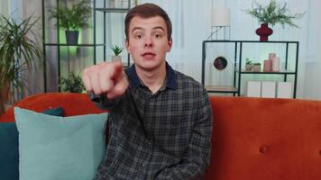 Young smiling man pointing to camera, choosing lucky winner, indicating, inviting, approve at home video