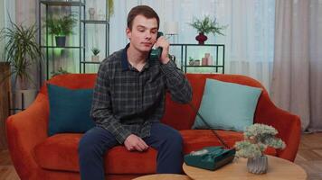 Man making retro telephone from 90s conversation with friends sitting call on couch at home in room video