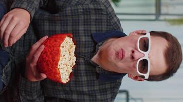 Man sitting on couch eating popcorn and watching interesting TV serial, sport game online at home video