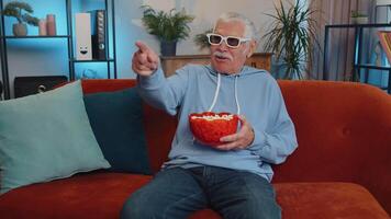 Man sitting on couch eating popcorn and watching interesting TV serial, sport game online at home video