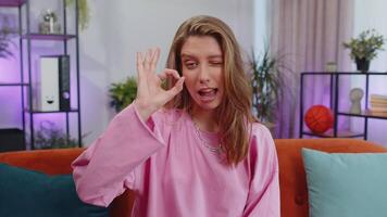 Happy cheerful young woman looking approvingly at camera showing ok gesture, positive like sign video