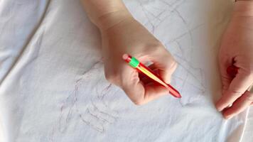 Hand drawing geometric patterns with red pen on white fabric surface transition sequence. video