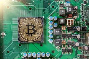 Gold souvenir coin Bitcoin on a computer circuit board background. photo