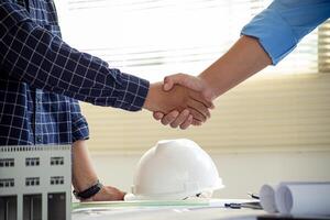 Architect and engineer construction workers shaking hands after successful collaboration. photo