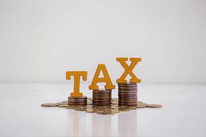 TAX Concept.Word tax put on coins with calculator and summary report on table. photo