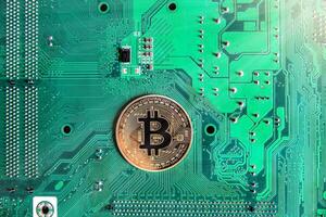 Gold souvenir coin Bitcoin on a computer circuit board background. photo