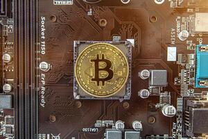 Gold souvenir coin Bitcoin on a computer circuit board background. photo