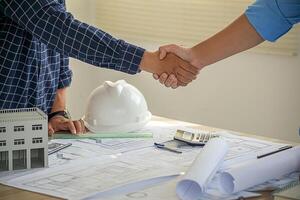 Architect and engineer construction workers shaking hands after successful collaboration. photo