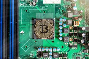 Gold souvenir coin Bitcoin on a computer circuit board background. photo