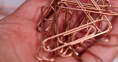 large-sized copper paper clips lie on white blank paper photo