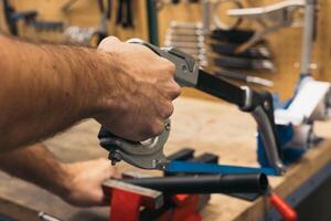 closeup of hand cutting a pipe with saw in workshop photo
