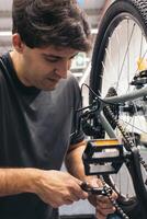 vertical portrait bicycle mechanic adjusting chain in workshop photo