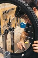 vertical closeup mechanic with tool to adjust bicycle spokes photo