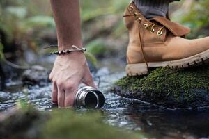 Hand and foot collecting water from river in forest photo