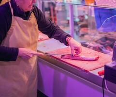 Closeup of Female Butcher Cutting Chicken Breast at Butcher Shop Counter photo