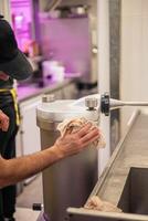 Precision Cleaning Butcher Attending to Sausage-Making Machine photo