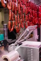 vertical portrait Vacuum Sealing Machine in Butcher Shop with Chorizos Hanging in Foreground photo