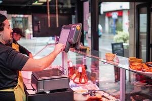 copyspace Butcher Using Scale at Butcher Shop Counter with Female Colleague Working in Background photo