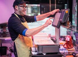 Smiling Butcher Weighing Customer's Meat Purchase on Scale photo