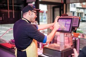 Butcher Weighing Customer's Meat Purchase from Behind the Counter photo
