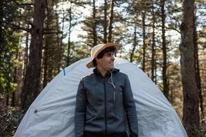 Smiling Explorer Camper Posing in Front of camping Tent at Summer Sunset in Forest photo