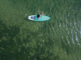 cenital copyspace above view Young Latin paddleboarding with board in the sea on a sunny summer day photo