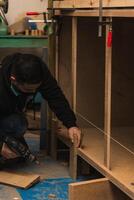 Latin Carpenter Using Drill to Repair Furniture in Carpentry Workshop photo