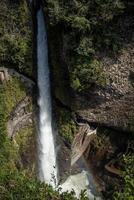 vertical Pailon del Diablo Waterfall Cascading Between Rocks Creating a Rainbow, Ecuador photo