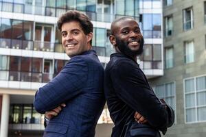 Smiling multicultural businessmen, african and latin, pose back to back while looking at the camera photo