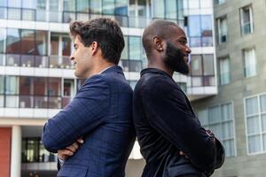 Confident multicultural businessmen in urban setting pose back-to-back photo