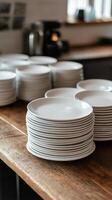 Stacked white plates on wooden table in a rustic environment photo