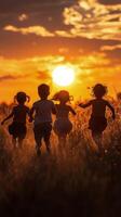 Children running towards a sunset in a grassy field during golden hour photo