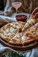 Deliciously cheesy pizza on a wooden board with fresh herbs and ros wine nearby photo