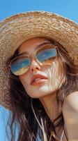 Woman wearing sunglasses and a straw hat in a natural outdoor setting on a sunny day photo