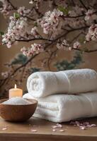 Relaxing spa setting with towels, candles, and cherry blossom branches in a serene environment photo