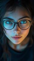 Young woman with glasses and captivating blue eyes in softly lit setting photo